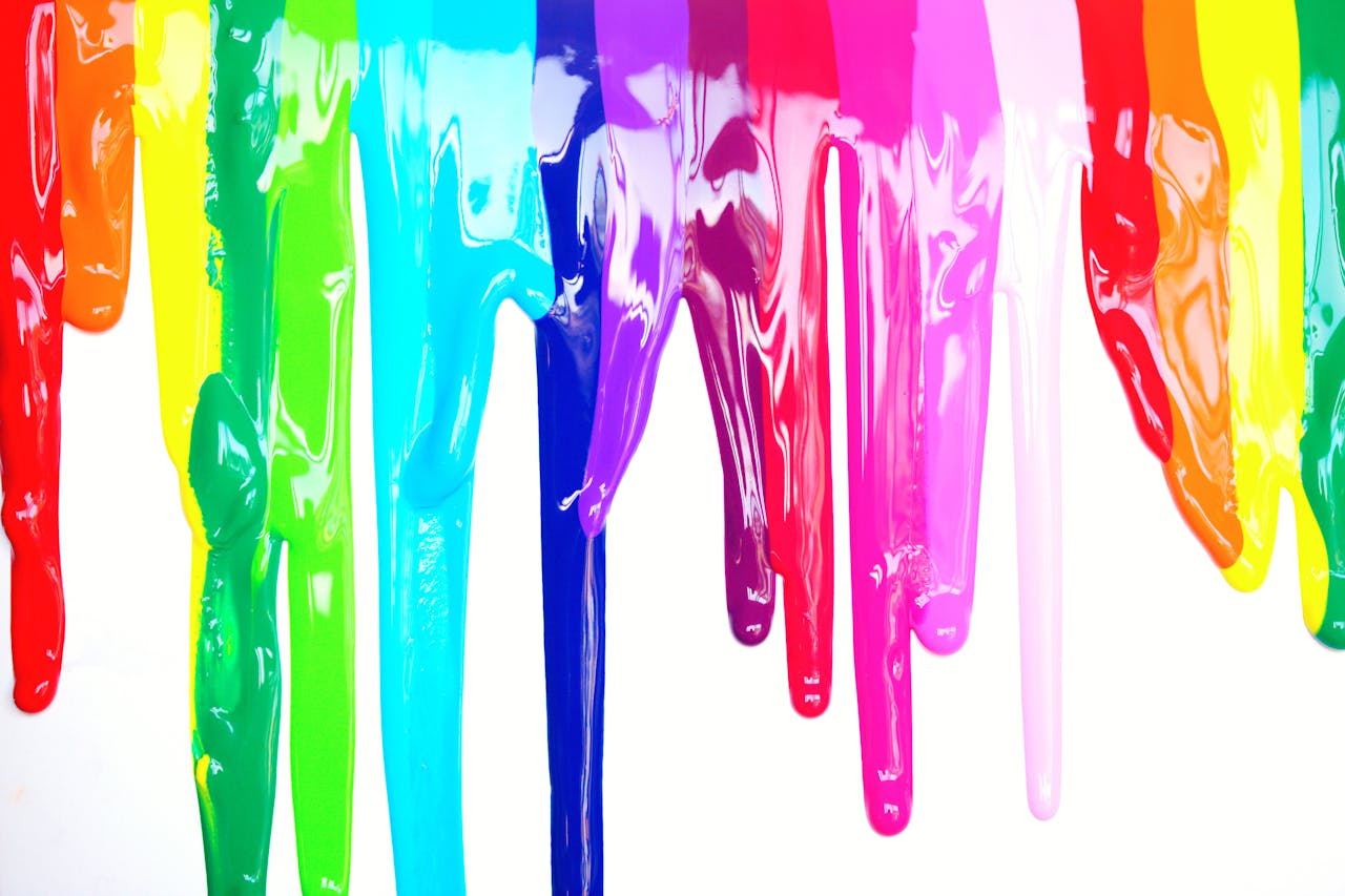 who-we-are Bright, colorful paints dripping creating a rainbow effect on a white background, symbolizing diversity and creativity.