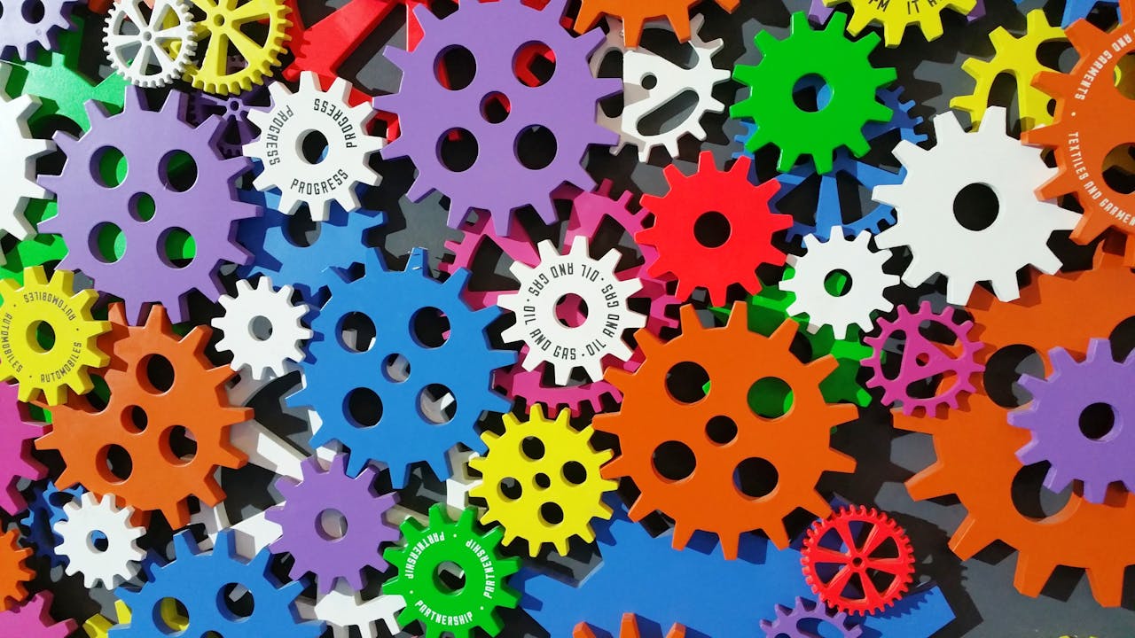 who-we-are A colorful arrangement of gears symbolizing creativity, innovation, and machinery in vibrant colors.